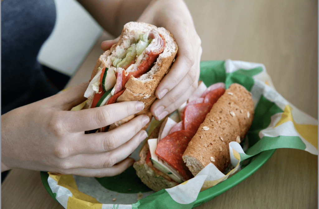 someone holding an italian bmt from subway